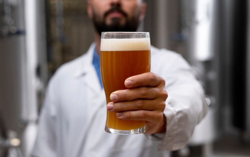 homem segurando copo cheio de cerveja em uma cervejaria